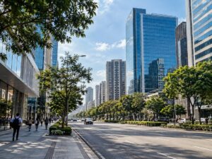 Avenida urbana com árvores, edifícios e pedestres distantes em uma manhã clara. Imagem ilustrativa.